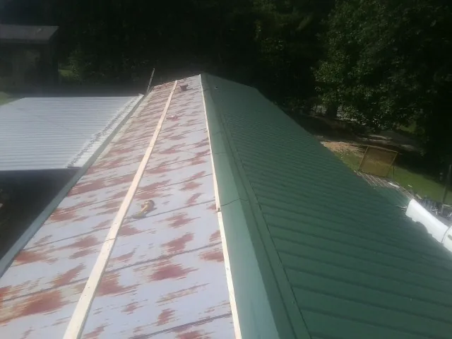 Old rusted panels beside newly installed green metal roofing — Wind Damage Roof Repair by Roofing Brothers in West Oneonta