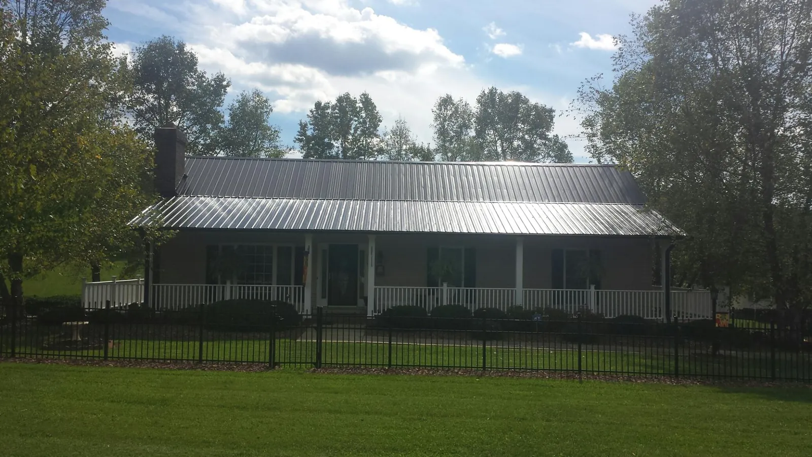 Gray metal roof on a brick ranch with a full width front porch — Gutter Guard Installation work by our crew in West Oneonta