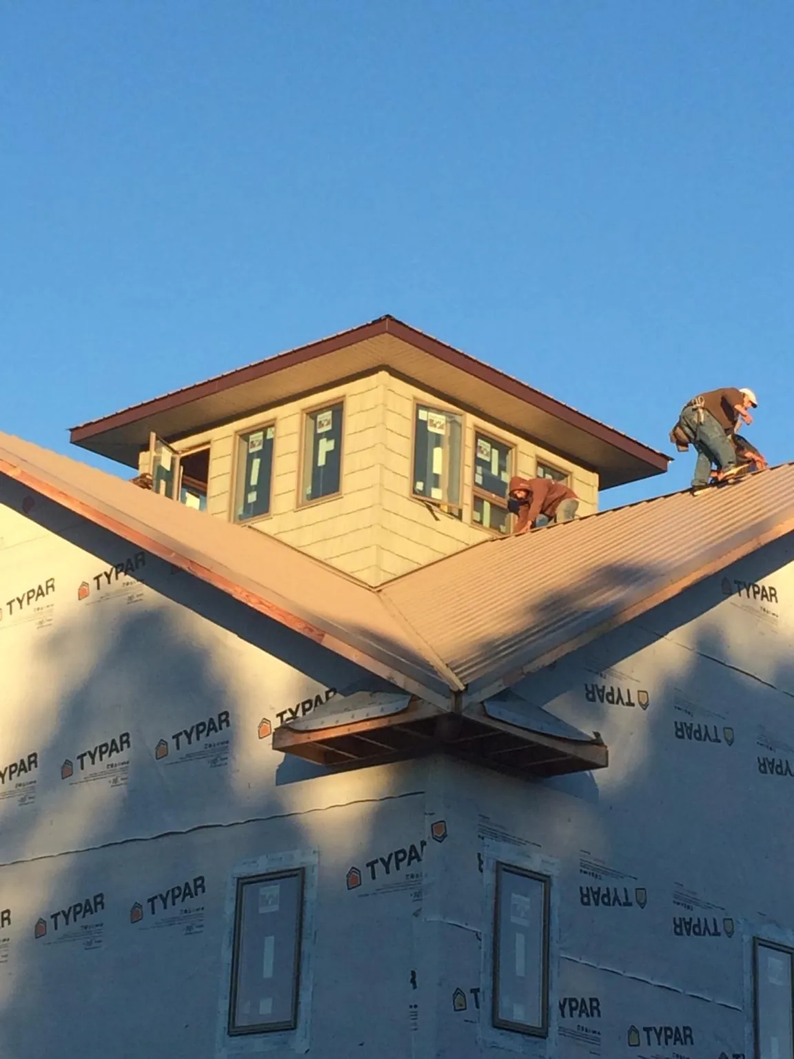 Roofers working around a rooftop cupola on a new metal roof at sunset — Roof Waterproofing in West Oneonta by Roofing Brothers